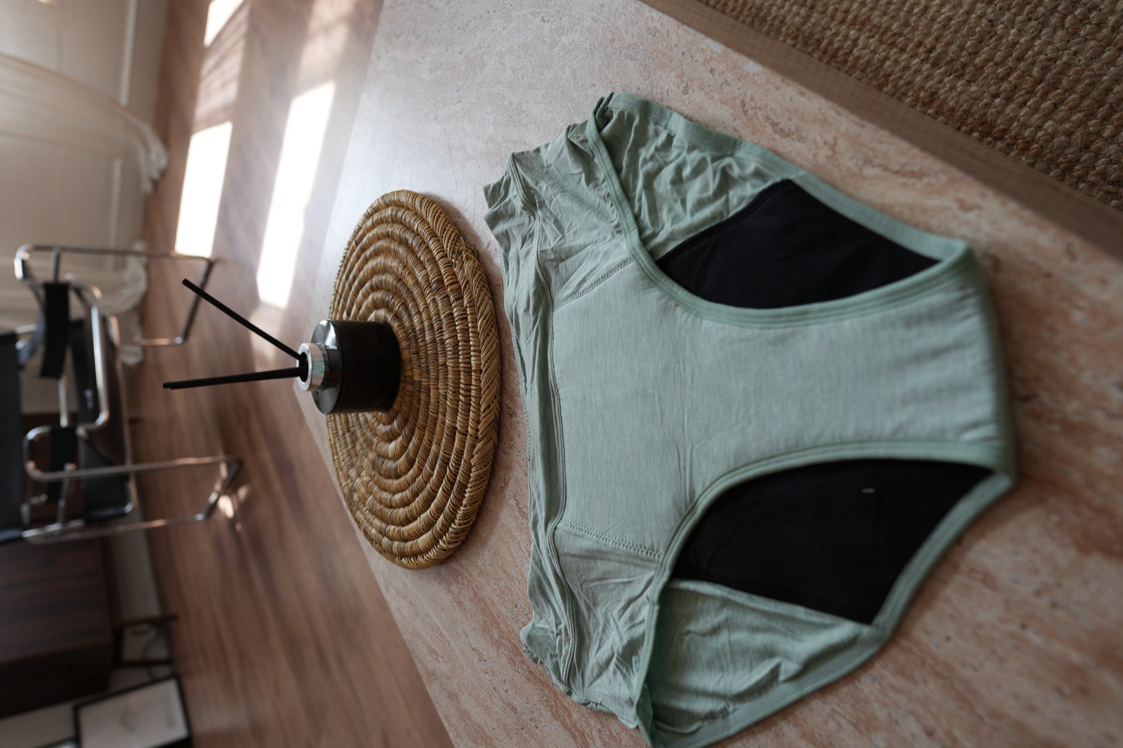 Sage green period underwear laid flat on a stone table